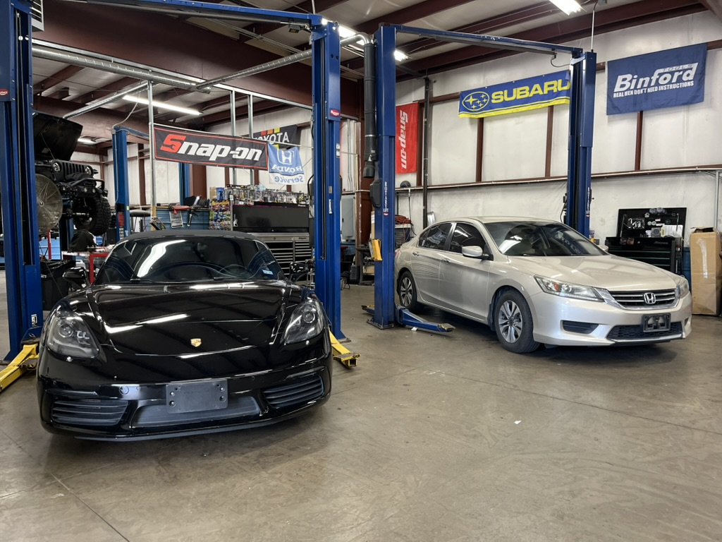 Porsche and Honda Accord raised on lifts in the service bays at Action Automotive in Colorado Springs