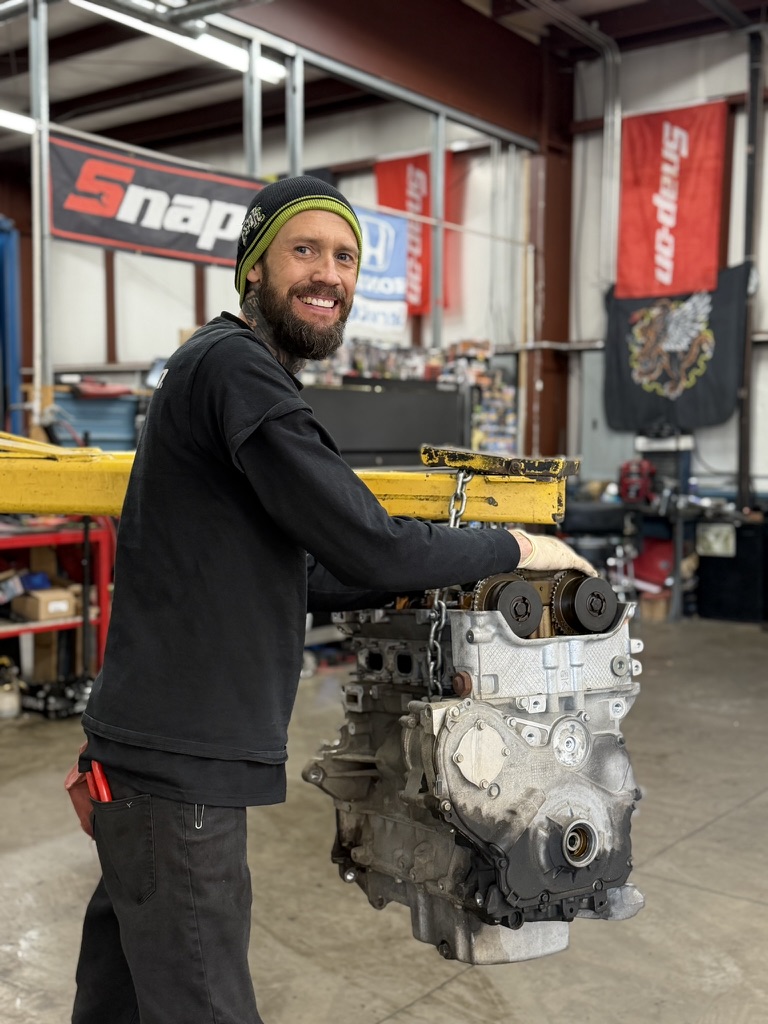 Technician working under the hood on an engine repair at Action Automotive in Colorado Springs